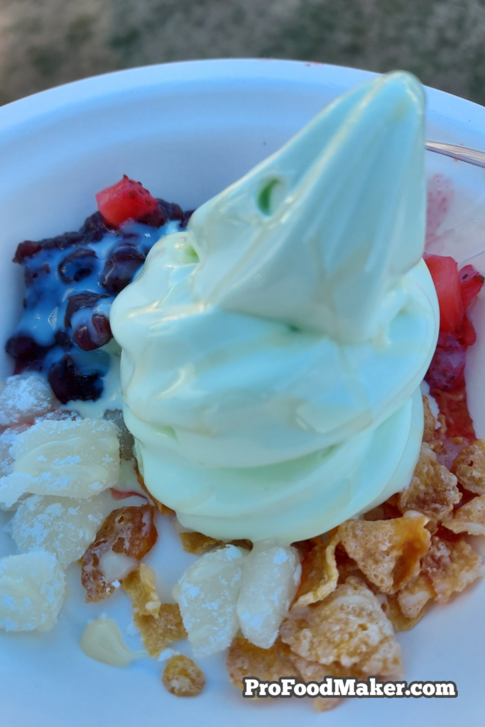 Close up shot of melon soft serve ice cream with mochi, red bean, strawberries, condensed milk & Frosted Flakes at Southern Smoke Festival.