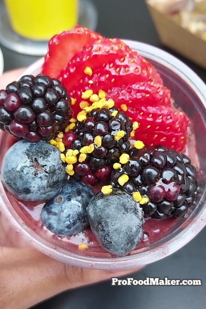 post houston photos food acai bowl. Sliced strawberries, blackberries and blueberries with honey drizzle and bee pollen in a small cup.