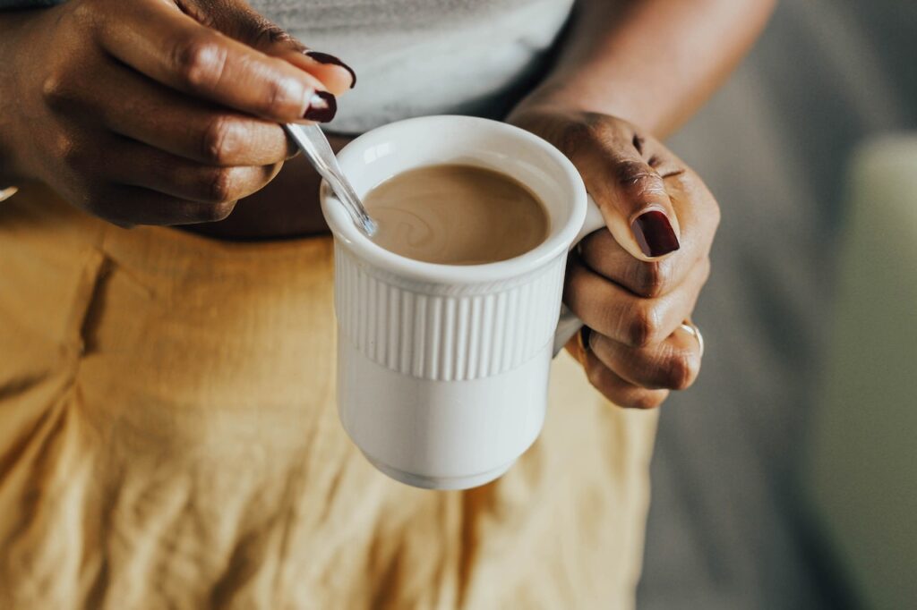 cafe owner. Black woman drinking coffee with a spoon in the cup.