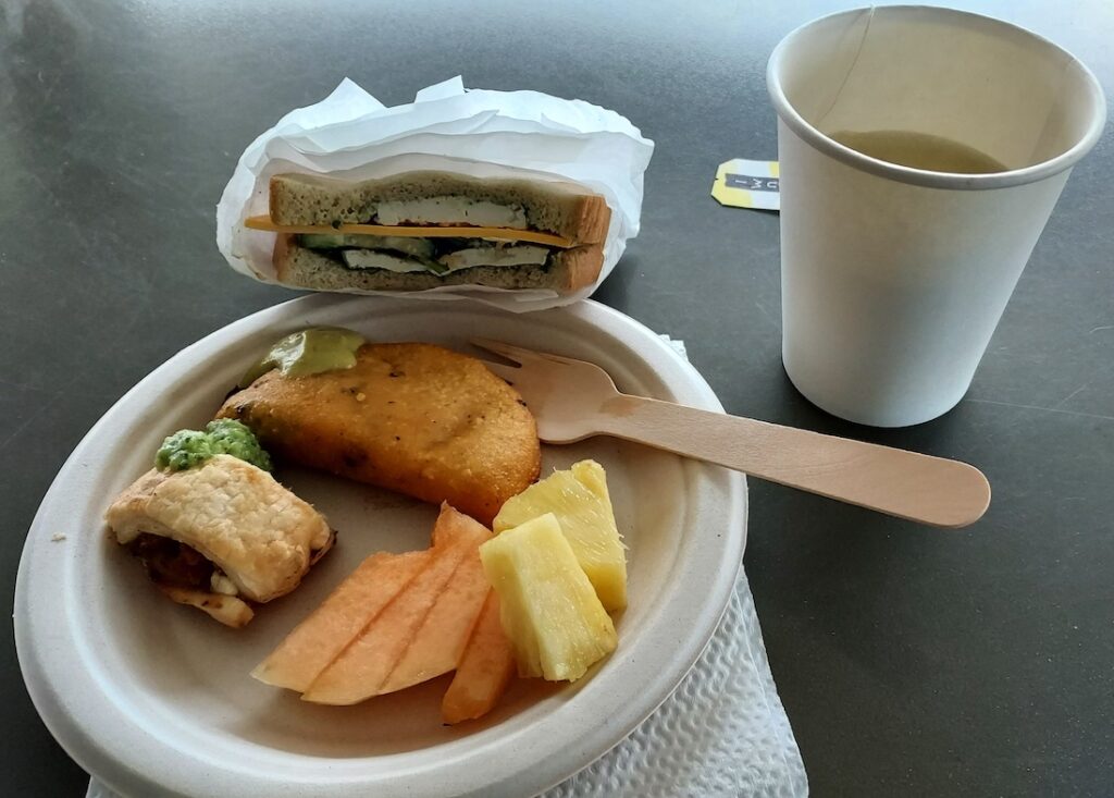 Women in ag events. Buffet breakfast of a vegan tofu sandwich, fresh pineapple and cantaloupe, an empanada with green sauce and tea.