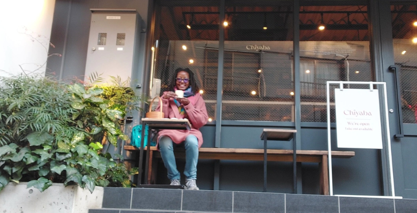 chiyaba tokyo review チャバ. The author sits outside of Chiyaba cafe on a bench enjoying wagashi in a small woven basket and a hot drink.