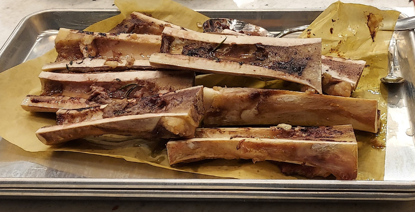 Seven roasted bones with bone marrow on a large baking sheet at a Hone Sharpen cooking class in Raleigh, NC.