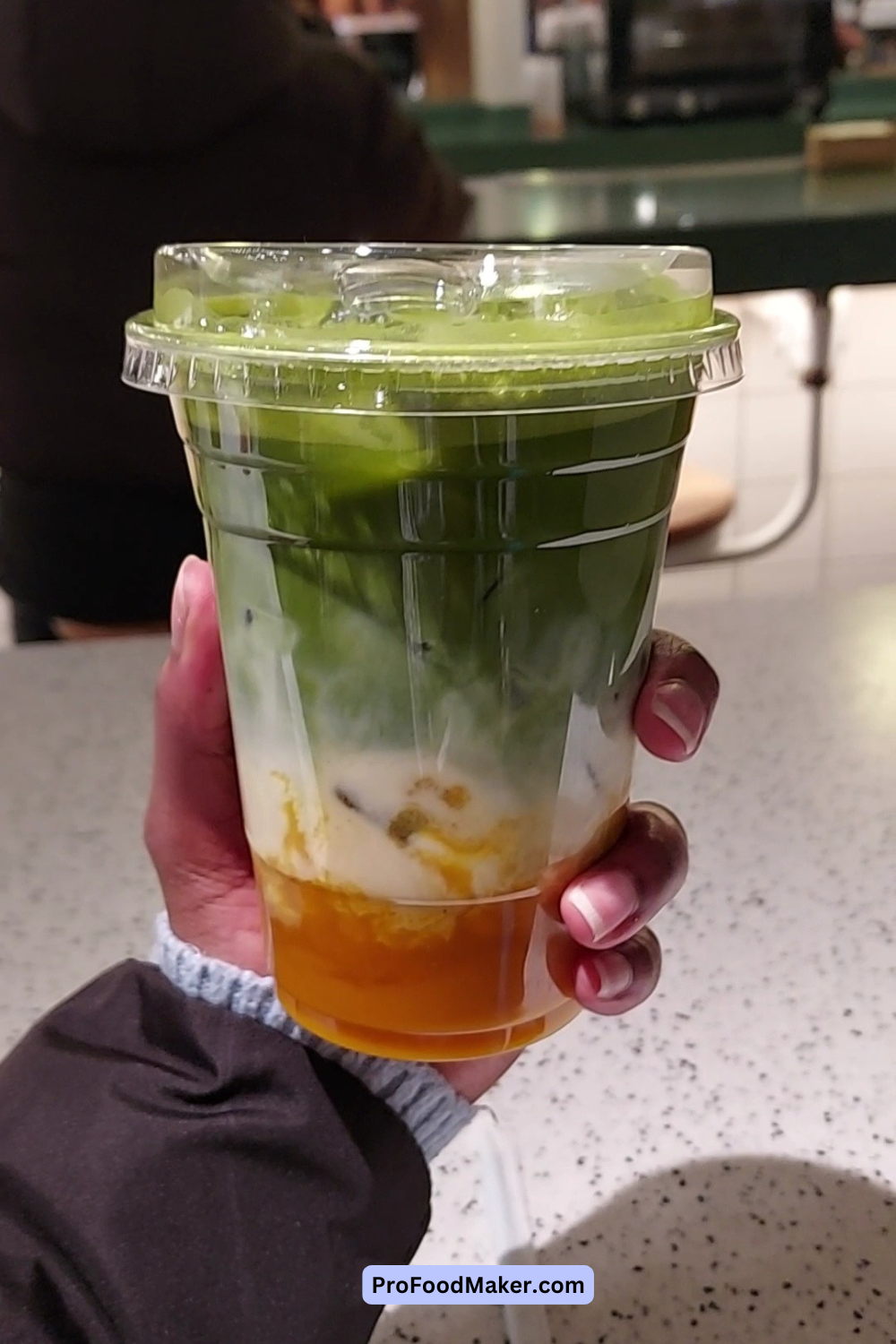 Matcha latte with mango in NYC. It's in a clear plastic cup.