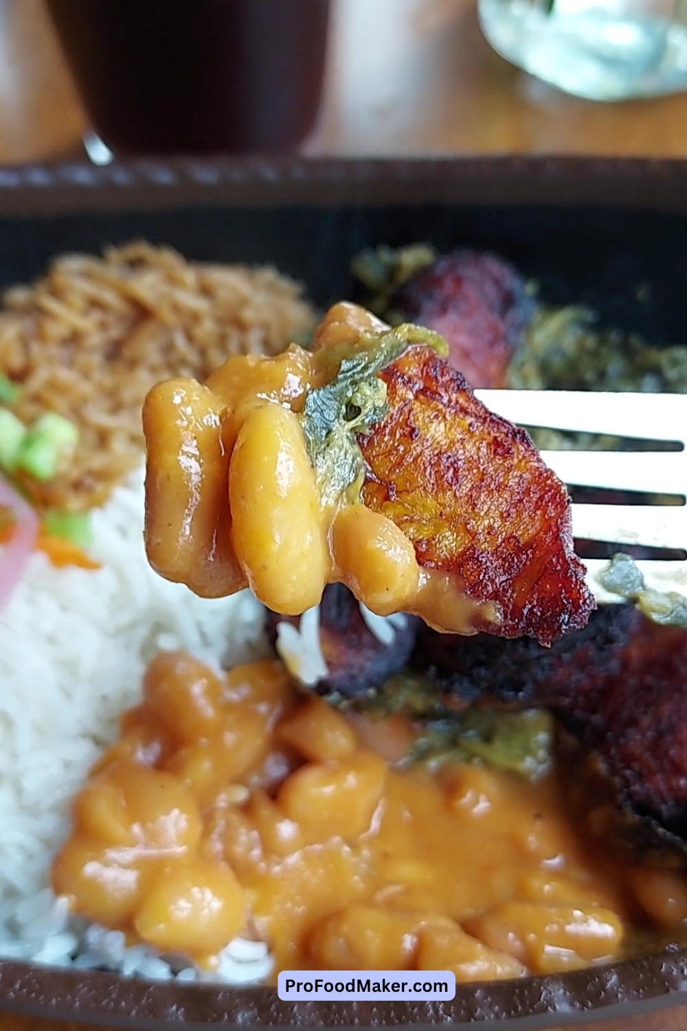 A close up shot of a piece of plantain, yellow beans and spinach on a fork.