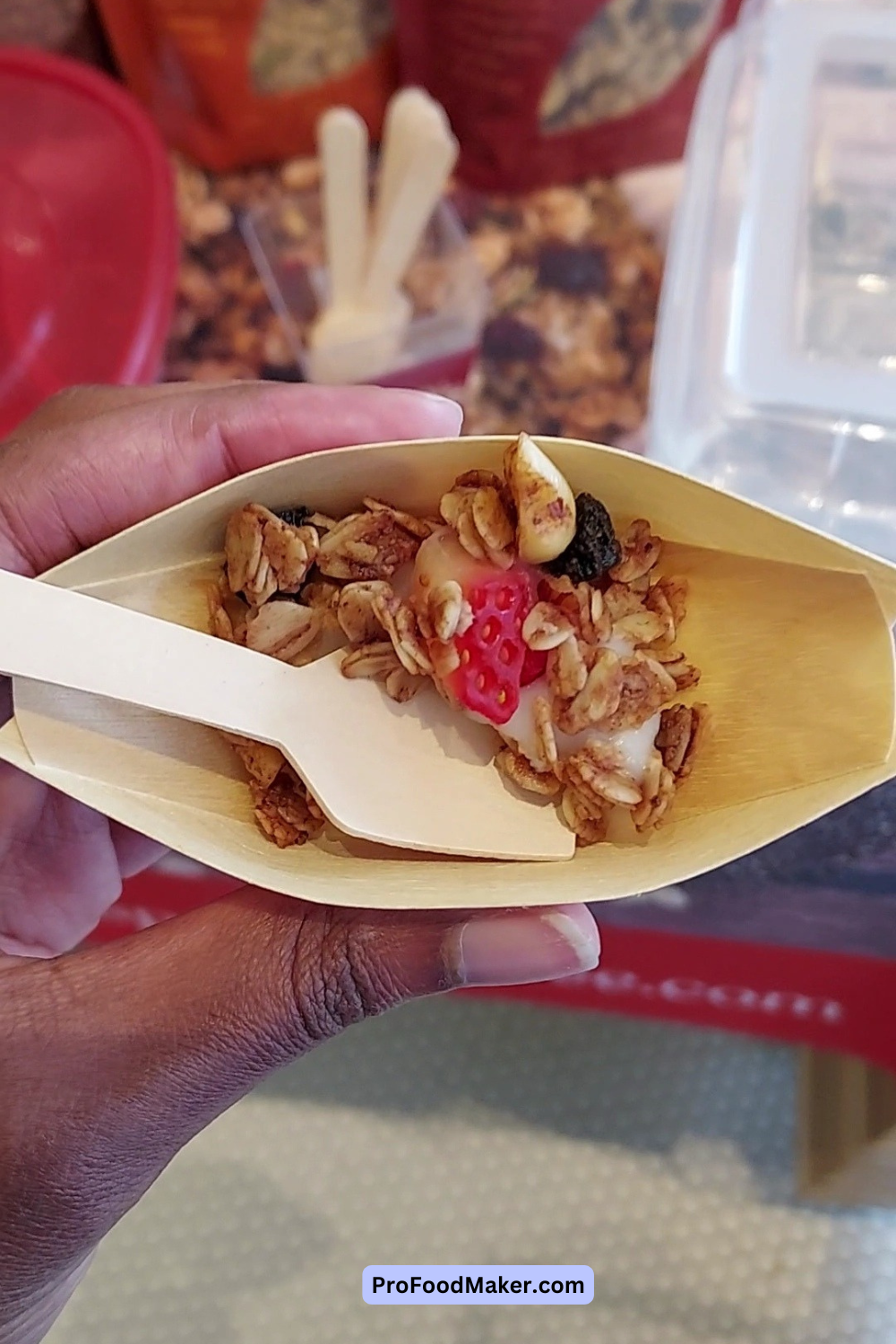Yogurt and granola in a small container with a wooden utensil.